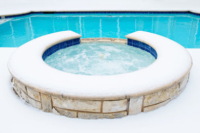 Réalisation d'une piscine naturelle et arrière tradition de taille moyenne et sur mesure avec un bain bouillonnant et des pavés en pierre naturelle.
