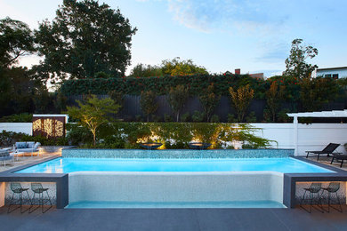 Photo of a contemporary back custom shaped above ground swimming pool in Melbourne with a water feature and concrete paving.