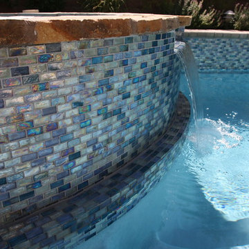 Iridescent blue 1” X 2” glass tile surrounds the pool and raised spa, on the rai