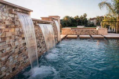 Pool fountain - large modern backyard stone and custom-shaped pool fountain idea in Houston