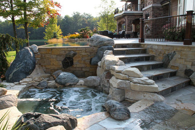 Пример оригинального дизайна: бассейн-инфинити среднего размера, произвольной формы на заднем дворе в морском стиле с покрытием из каменной брусчатки и джакузи