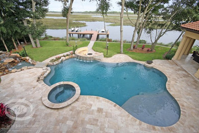Inspiration for a large tropical backyard stone and custom-shaped infinity pool remodel in Jacksonville