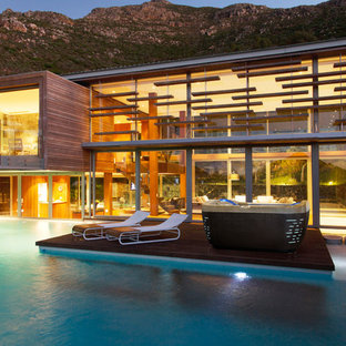 Ispirazione per un'ampia piscina naturale minimalista personalizzata dietro casa con una vasca idromassaggio e pedane