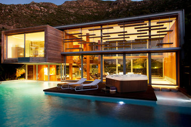Пример оригинального дизайна: большой бассейн на заднем дворе в стиле модернизм с джакузи