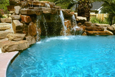 Ejemplo de piscina con fuente alargada grande tipo riñón en patio trasero