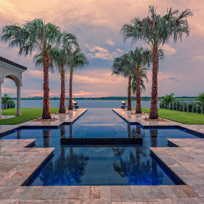 Hot tub - tropical backyard custom-shaped infinity hot tub idea in Houston
