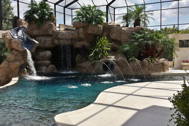 Foto de piscina con tobogán alargada actual grande a medida en patio trasero