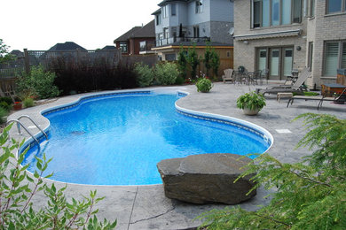 На фото: большой естественный бассейн произвольной формы на заднем дворе в классическом стиле с покрытием из бетонных плит с