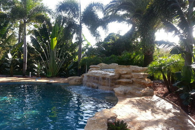 Foto de piscina con fuente natural exótica pequeña a medida en patio trasero con adoquines de piedra natural