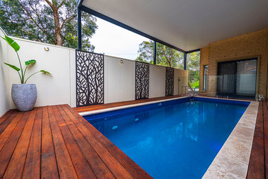 Imagen de piscina alargada moderna de tamaño medio rectangular en patio lateral con entablado