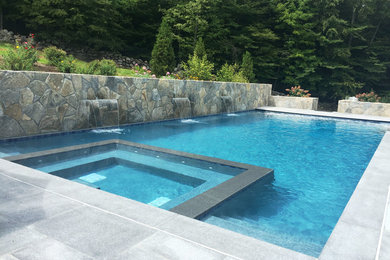 Pool fountain - large contemporary backyard stone and rectangular pool fountain idea in New York