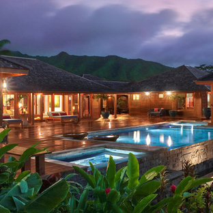 Immagine di una piscina a sfioro infinito tropicale rettangolare di medie dimensioni e dietro casa con pedane