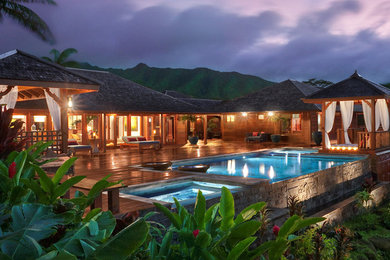 Immagine di una piscina a sfioro infinito tropicale rettangolare di medie dimensioni e dietro casa con pedane