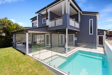 Imagen de piscina alargada contemporánea de tamaño medio en forma de L en patio trasero con adoquines de hormigón