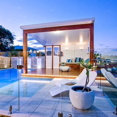 Example of a mid-sized minimalist backyard stone and custom-shaped aboveground pool house design in Brisbane
