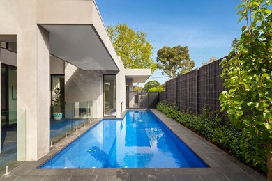 Cette image montre une piscine design en L avec des pavés en pierre naturelle.