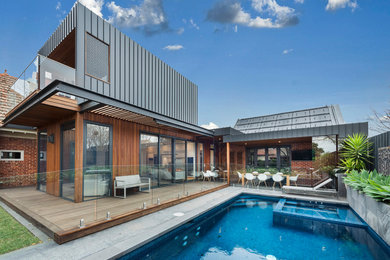Идея дизайна: большой бассейн произвольной формы на заднем дворе в современном стиле с домиком у бассейна и покрытием из каменной брусчатки