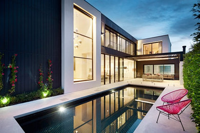 Modelo de piscinas y jacuzzis alargados minimalistas rectangulares en patio trasero con losas de hormigón