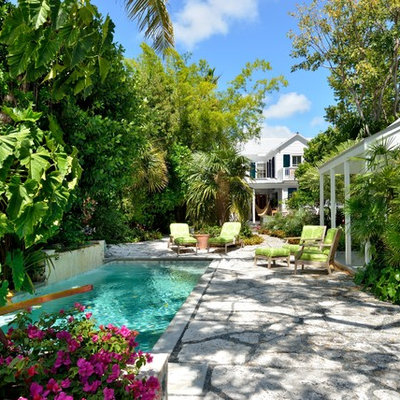 Example of an island style backyard concrete paver and rectangular pool house design in Miami