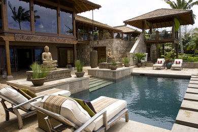 Foto de piscina tropical de tamaño medio rectangular en patio trasero con adoquines de hormigón