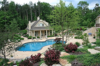 Modelo de casa de la piscina y piscina natural grande a medida en patio trasero con losas de hormigón