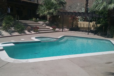 Imagen de piscina de estilo americano de tamaño medio a medida en patio trasero con losas de hormigón