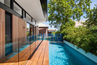 Modelo de piscina alargada actual pequeña rectangular en patio lateral con entablado