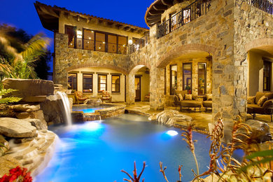 Mid-sized tuscan backyard stone and custom-shaped hot tub photo in Orange County