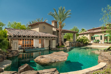 Diseño de piscina con fuente natural mediterránea a medida en patio trasero con adoquines de piedra natural