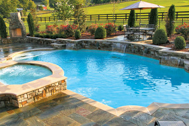 Foto de piscina con fuente alargada actual de tamaño medio tipo riñón en patio trasero con adoquines de piedra natural