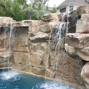 Foto di una grande piscina tropicale personalizzata dietro casa con un acquascivolo e pavimentazioni in pietra naturale