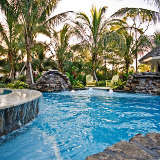 Mid-sized tropical backyard custom-shaped pool in Miami with a hot tub and natural stone pavers.