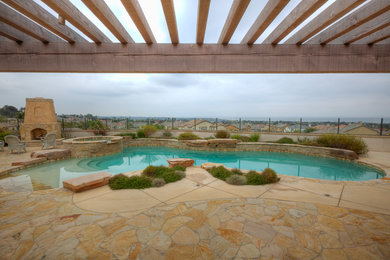 Esempio di una piscina american style personalizzata di medie dimensioni e dietro casa con una vasca idromassaggio e pavimentazioni in pietra naturale