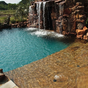 Lagoon style swimming pool with waterfall grotto with spa inside.
