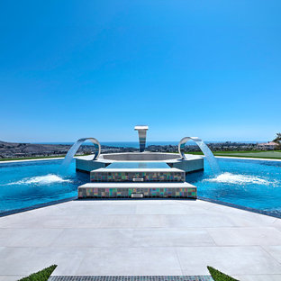 Bild på en stor funkis anpassad infinitypool på baksidan av huset, med marksten i betong och en fontän