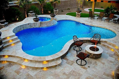 Ejemplo de piscinas y jacuzzis alargados actuales de tamaño medio a medida en patio trasero con adoquines de piedra natural
