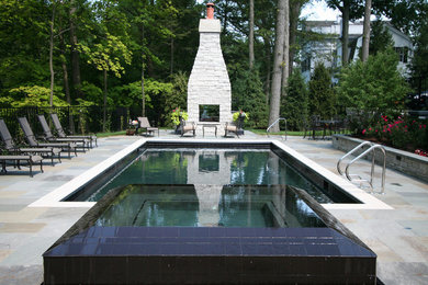Foto di una piscina monocorsia chic rettangolare di medie dimensioni e dietro casa con pavimentazioni in pietra naturale e una vasca idromassaggio