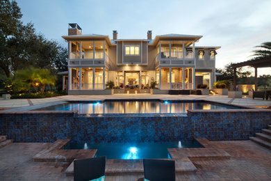 This is an example of a large contemporary back rectangular infinity swimming pool in Orlando with brick paving.