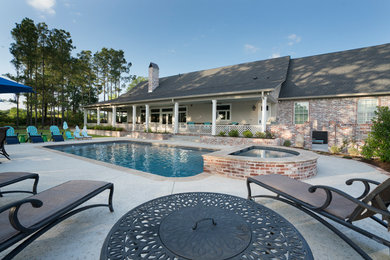 Immagine di una piscina naturale country rettangolare di medie dimensioni e dietro casa con una vasca idromassaggio e lastre di cemento