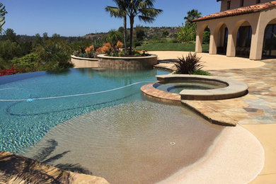 Medium sized coastal back custom shaped infinity hot tub in San Diego with concrete slabs.