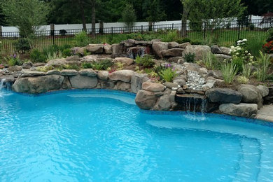 This is an example of a large beach style side custom shaped swimming pool in New York with concrete paving.