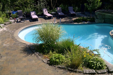 Ejemplo de piscina natural tradicional de tamaño medio a medida en patio trasero con adoquines de hormigón