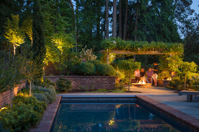 Ejemplo de piscina alargada clásica grande rectangular en patio trasero con adoquines de ladrillo