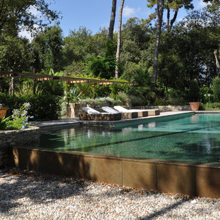 Immagine di un'ampia piscina a sfioro infinito minimal rettangolare con una dépendance a bordo piscina e pavimentazioni in pietra naturale