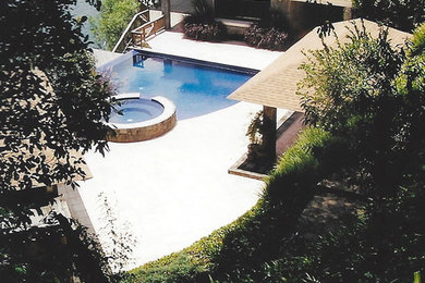 This is an example of a large world-inspired front custom shaped infinity hot tub in Other with concrete slabs.