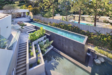 Diseño de piscina alargada contemporánea extra grande a medida en patio con losas de hormigón