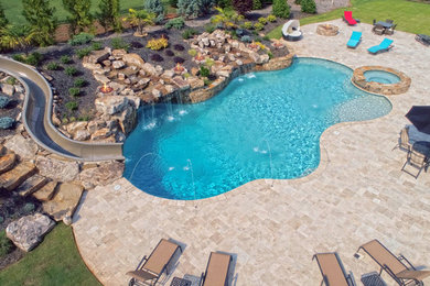 Modelo de piscina con tobogán natural grande a medida en patio trasero con entablado