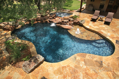 Immagine di una piscina naturale stile rurale personalizzata di medie dimensioni e dietro casa con una vasca idromassaggio e pavimentazioni in pietra naturale
