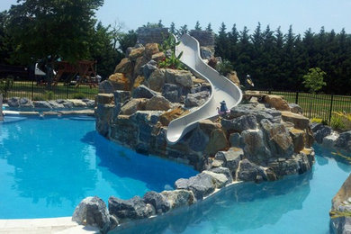 Diseño de piscina con tobogán natural tradicional grande a medida en patio trasero