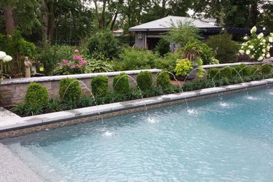 Ejemplo de piscina con fuente natural clásica de tamaño medio rectangular en patio trasero con losas de hormigón